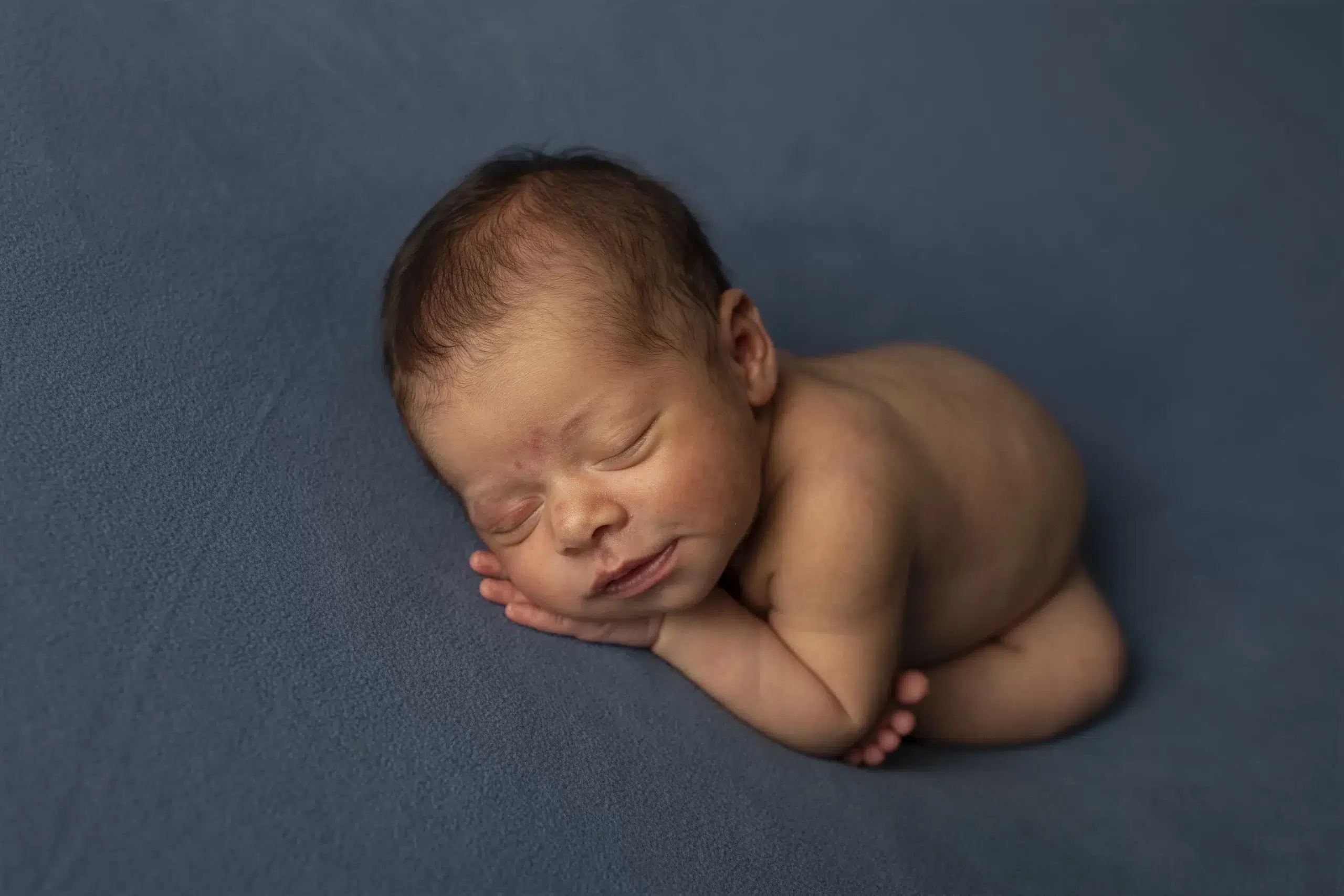 Bebê recém-nascido dormindo em posição fetal, capturado antes da pós-produção