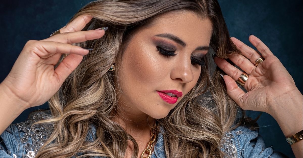 Mulher com maquiagem sofisticada e cabelos ondulados em pose expressiva