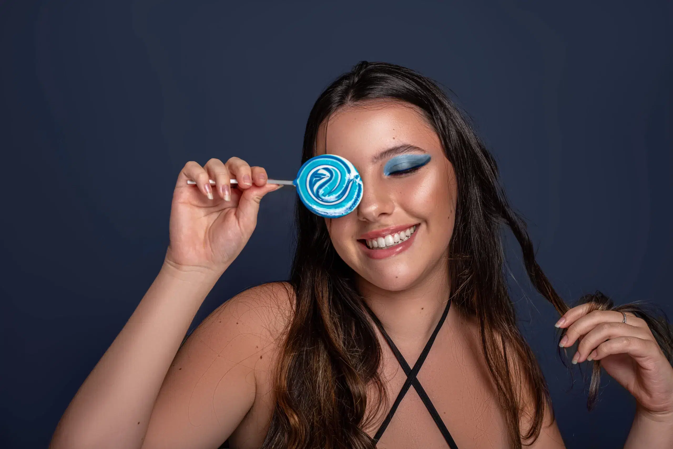 Modelo sorridente segurando um pirulito azul diante do olho, pós-produção